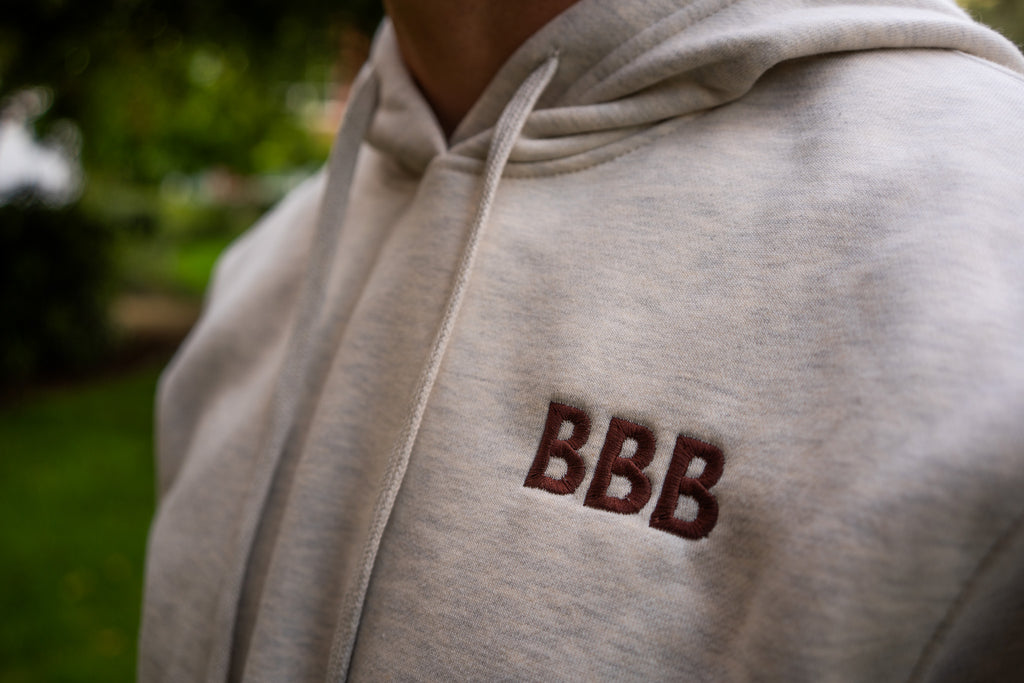 Light gray hoodie with 'BBB' logo on a blurred outdoor background