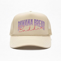 Khaki cap with 'Banana Bread Baddie' text in purple and pink on a white background