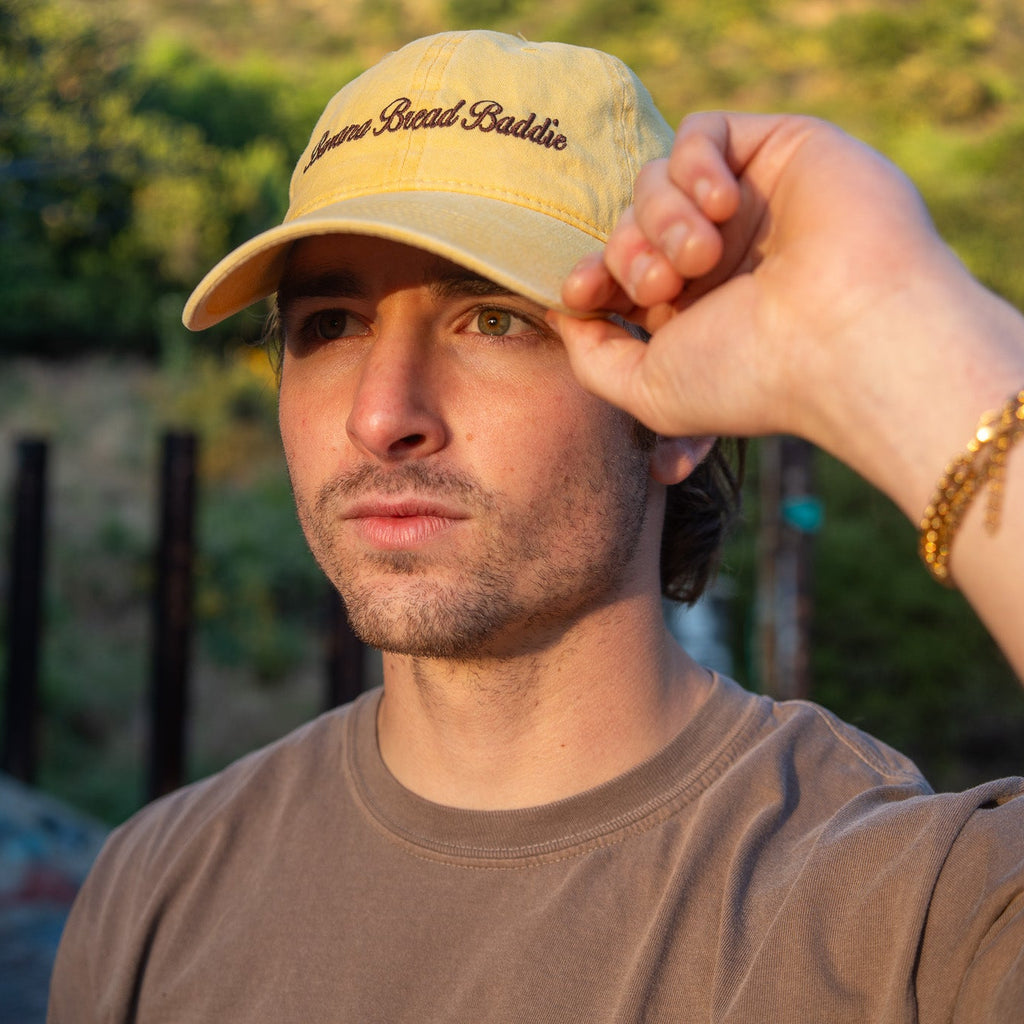 Jacob Mathiasmeier wearing a faded yellow cap with text, adjusting it outdoors.