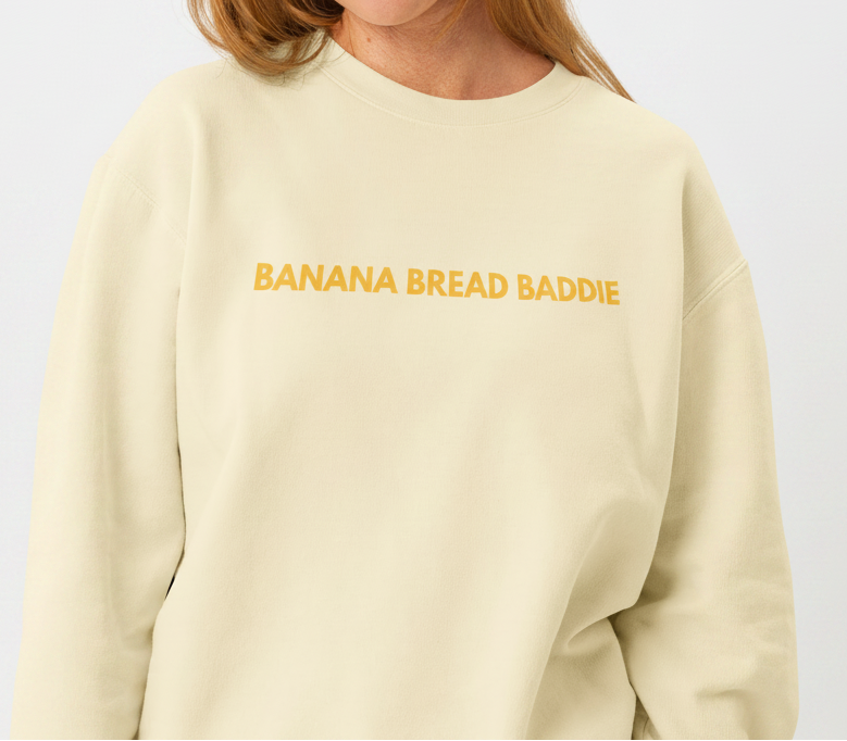 Woman wearing a beige sweatshirt with a gold logo on a white background